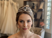 Load image into Gallery viewer, Silver tiara on a white surface with a wedding dress and jewelry in the background