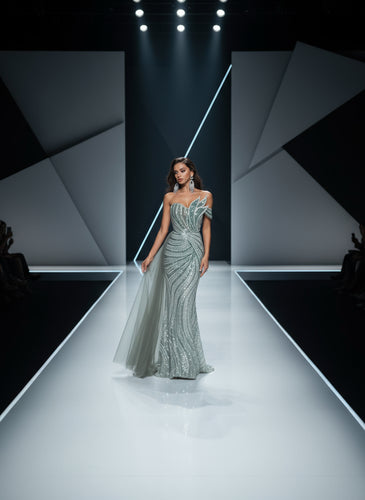 Model walking on a fashion show runway wearing a sparkling silver gown.